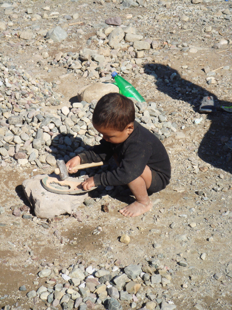 “A toddler wearing a black shirt and no pants—never mind shoes—was hitting at a rock with a hammer as a playtime activity….” (Noaman G. Ali)