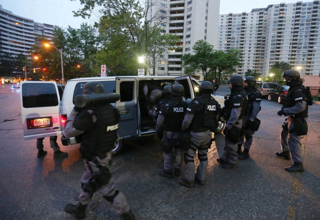 One of the 42 tactical Police units involved in the Project Traveller raids standing in front of 320, 330 and 340 Dixon Road.   (Steve Russell/Toronto Star)