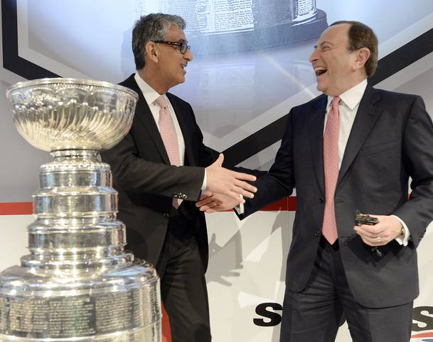 NHL Commissioner Gary Bettman to the right of Rogers President and CEO Nadir Mohamed, shaking hands after brokering a deal for Rogers to get monopoly rights over the broadcasting of NHL games.