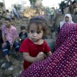 A Palestinian woman carries her daughter past rubble from a home which was destroyed in an Israeli air strike in Beit Hanoun, in the northern Gaza Strip, on July 9, 2014. (Photo: AFP - Mohammed Abed).